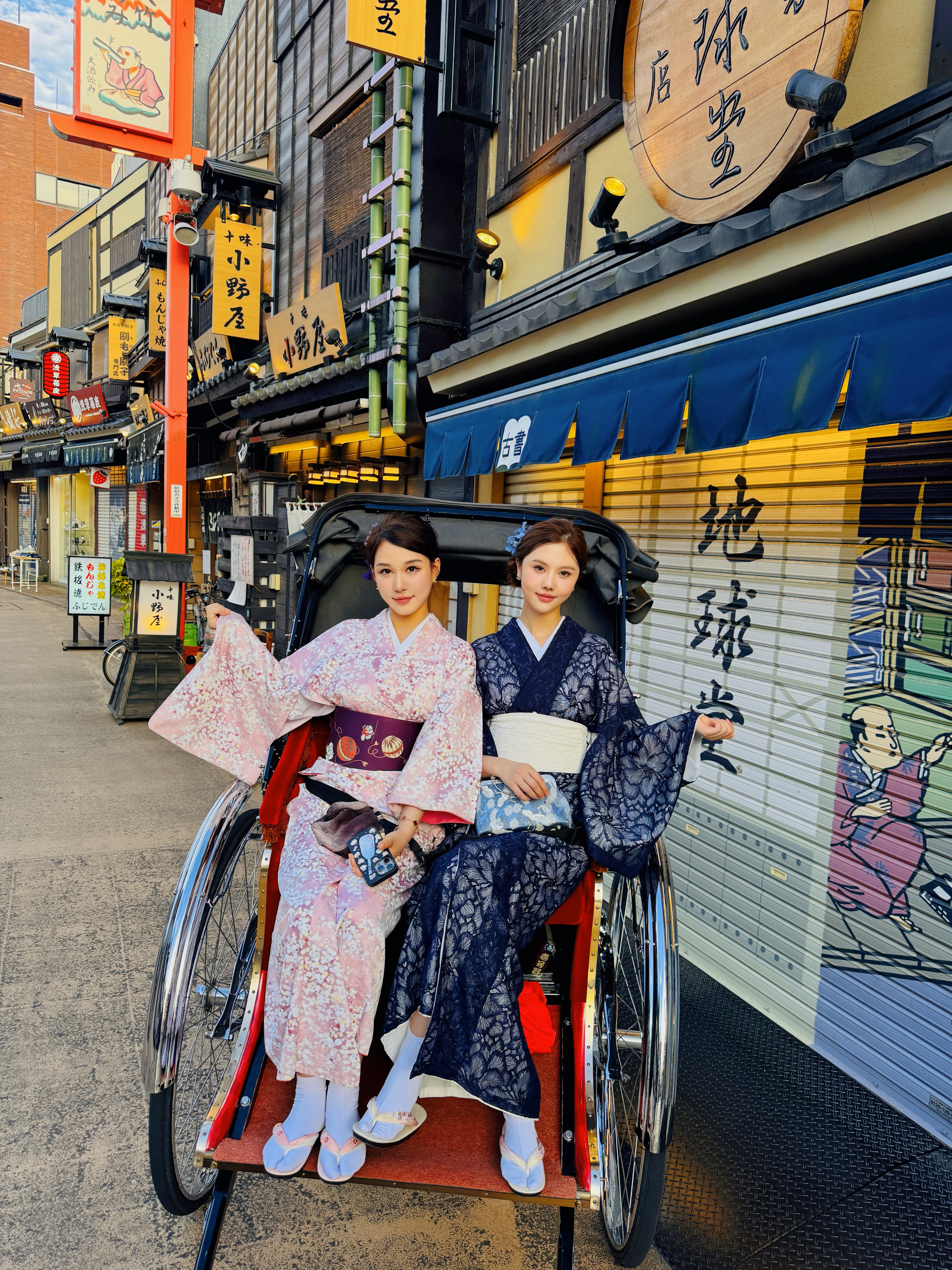 Two guests in kimono seated in a rickshaw